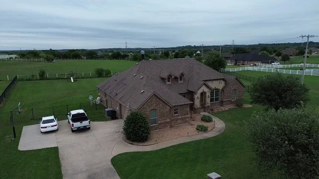 Before — original brown shingle roof on the brick and stone home